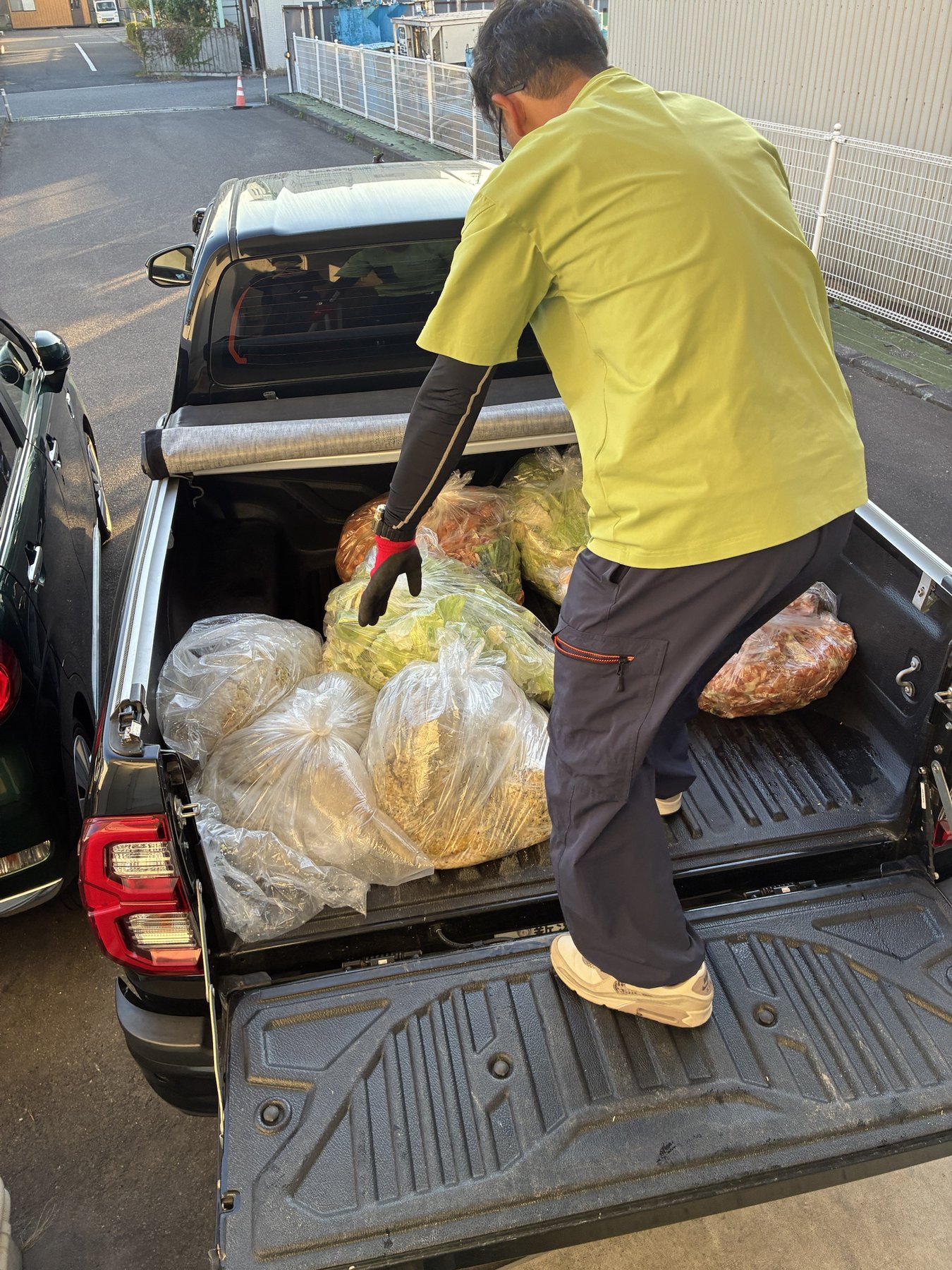 給食の食品残渣が入った袋を車の荷台に積み込む回収作業の様子