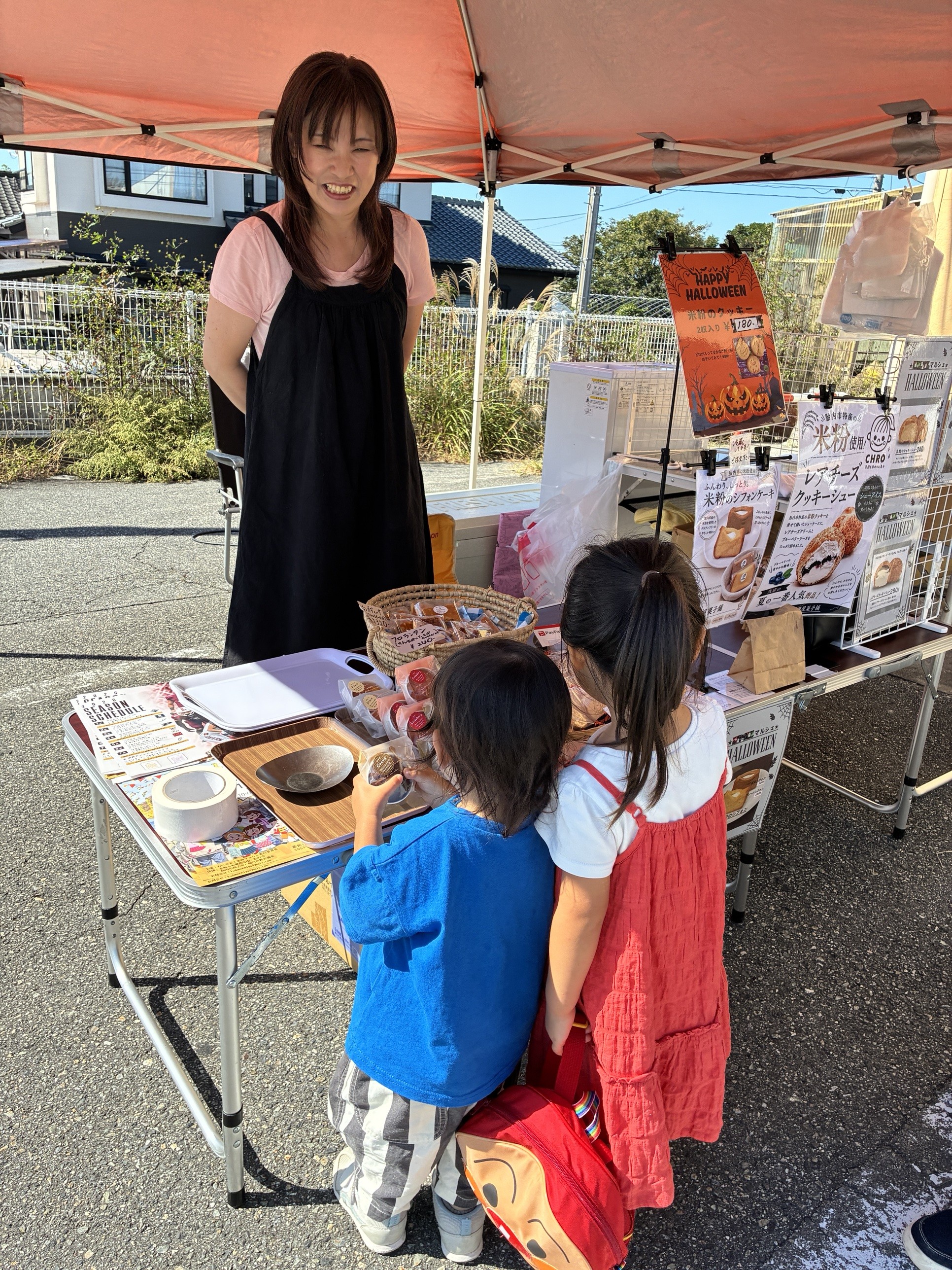米粉のお菓子が並ぶマルシェのテントで、お菓子を選ぶ子どもたち