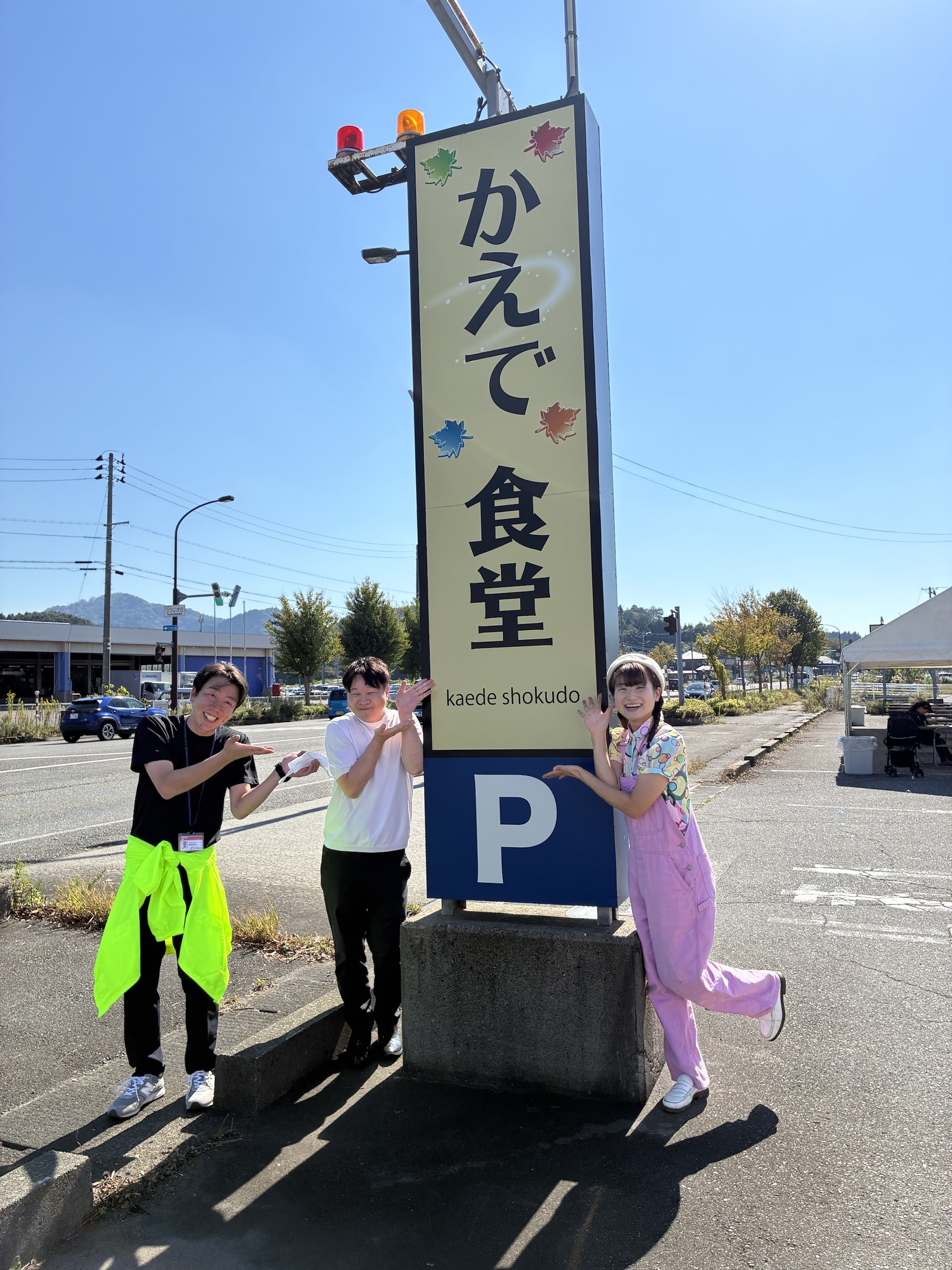 かえで食堂の看板の前で笑顔を見せる当社社員と社長、シャボン玉パフォーマー